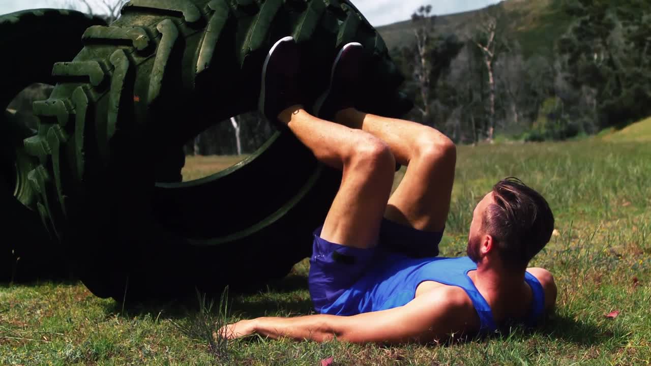 hombre realizando ejercicios de piernas con neumáticos en el campamento de entrenamiento
