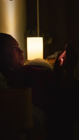 woman using phone in bed at night