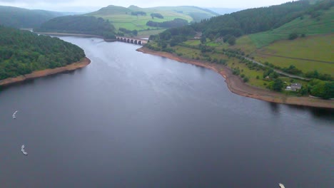 drone camera glides above a wide reservoir, revealing a bridge, green hills, and a rural landscape under soft daylight with smooth, steady movement
