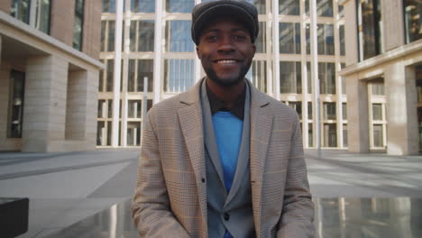 portrait of cheerful black businessman working on laptop outdoors