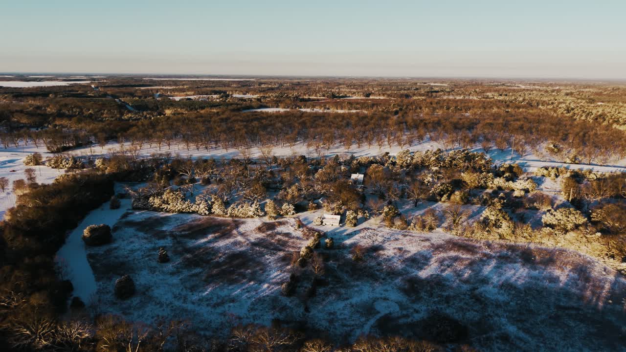 A serene drone shot tracking left along a snow-covered treeline, partially concealing a quiet highway in South Georgia. Captured during a rare winter snowfall.