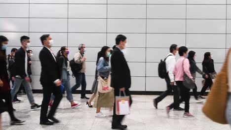 commuters wearing protective masks walk through hong kong mtr subway station early morning in central district, hong kong.