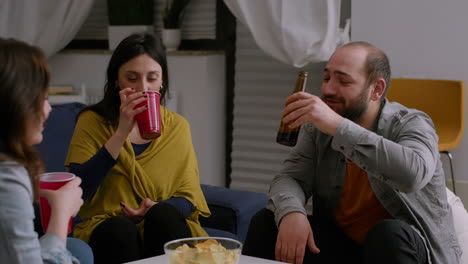 multi-ethnic friends socializing during night home party while resting on couch