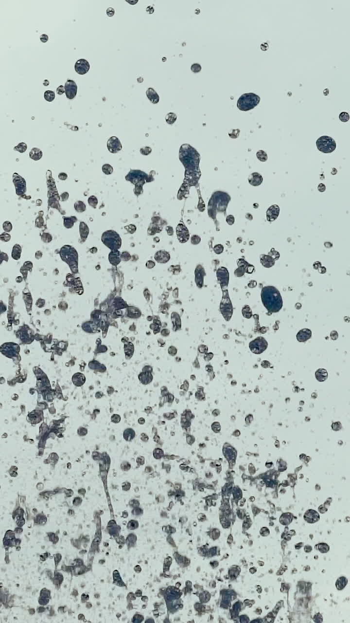 Close-up of fountain water droplets on sunlight. Water splashing. Slow motion Vertical video