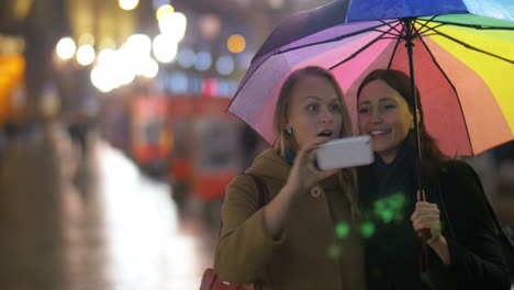 female friends making selfie under rainbow umbrella