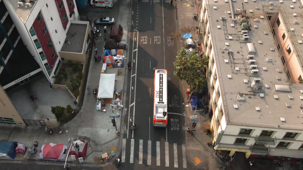 Aerial view of an urban street with a bus and a homeless encampment