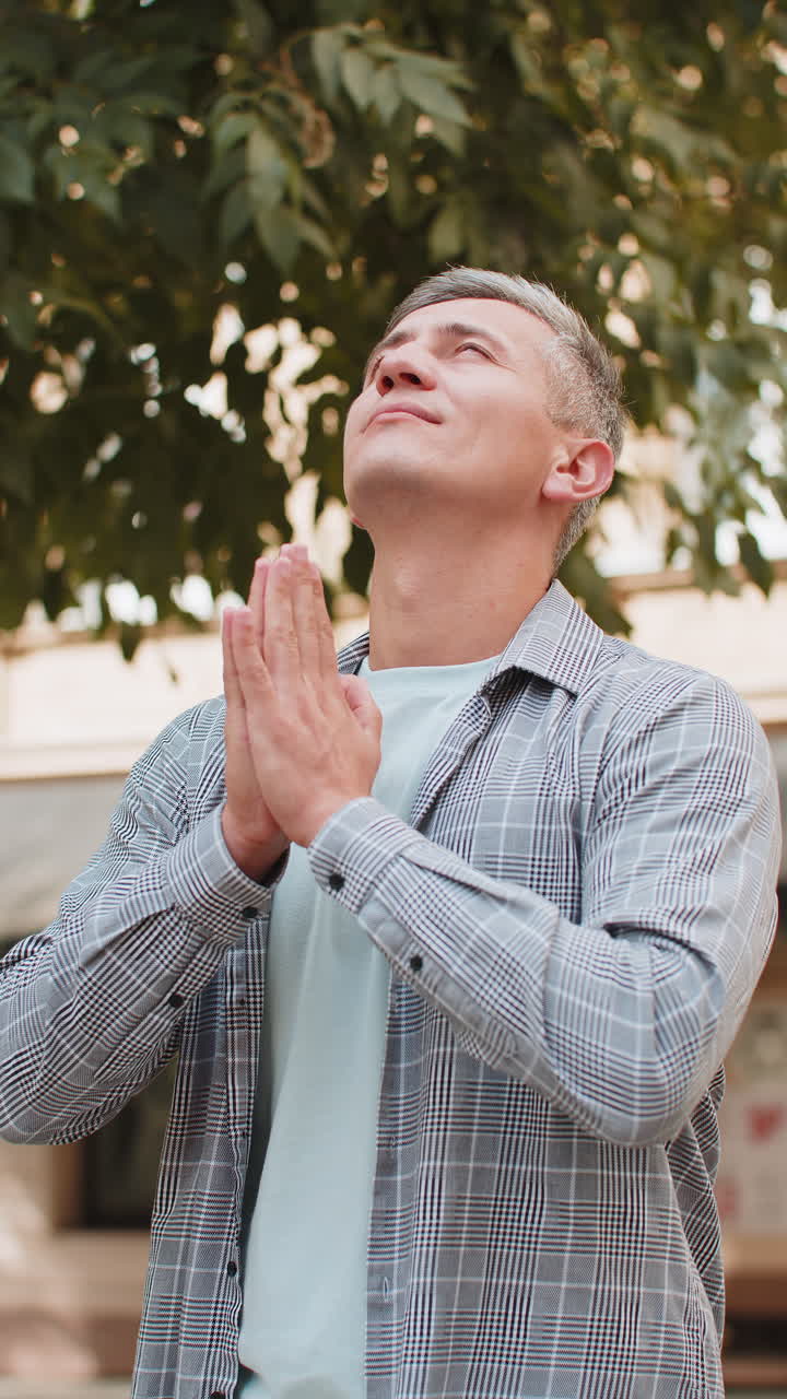백인 성숙한 남자 관광객은 눈을 감고 하나님께 기도하고 도시 거리에서 축복을 구합니다.