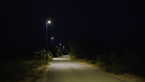 a dark country road at night illuminated by streetlights