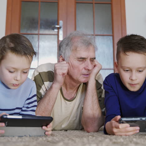 curious grandfather learning from his grandchildren how to use a tablet. peaceful pastime.