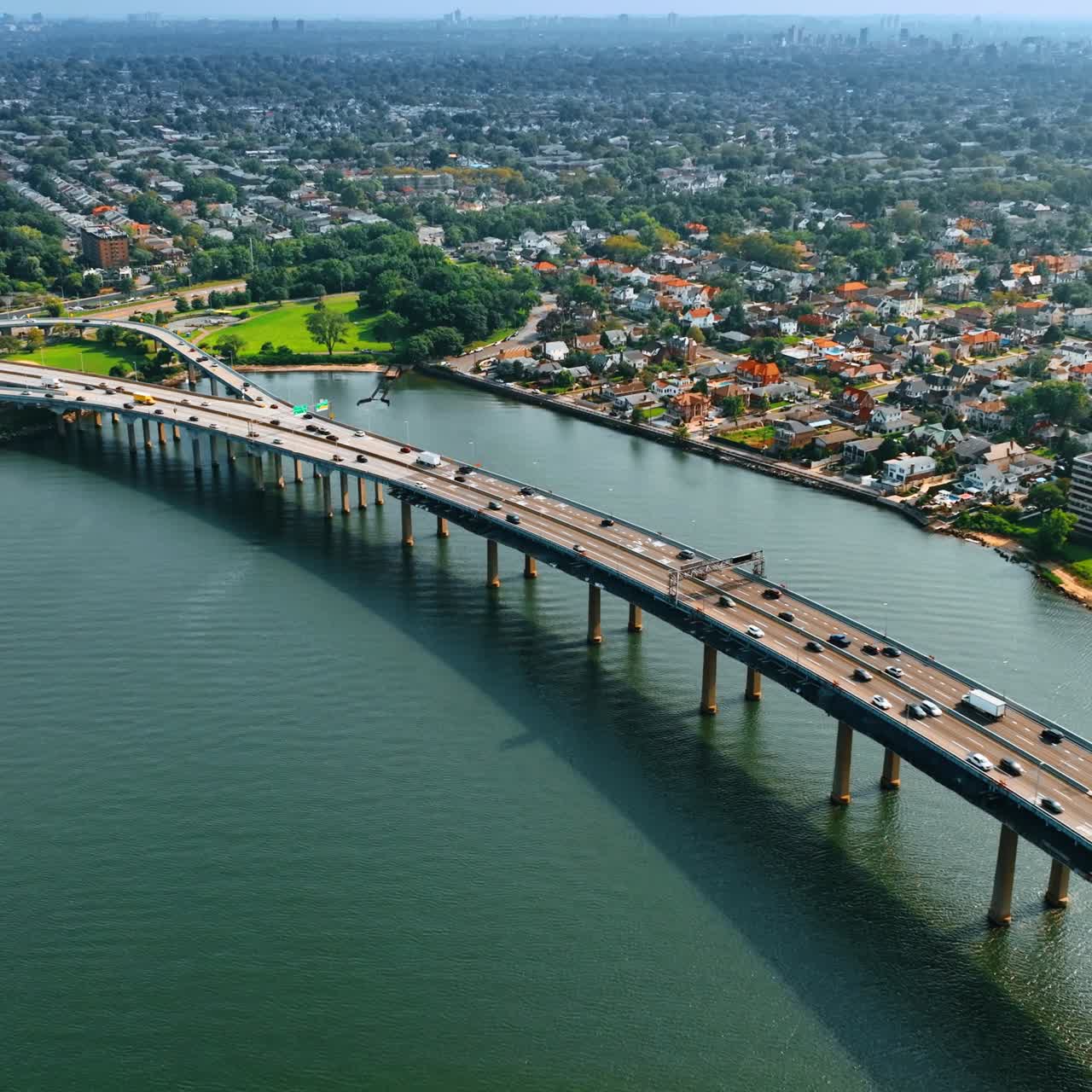 Grande e bellissimo ponte sull'acqua verde mare. Vasto paesaggio urbano soleggiato con tanto verde sullo sfondo. Vista dall'alto