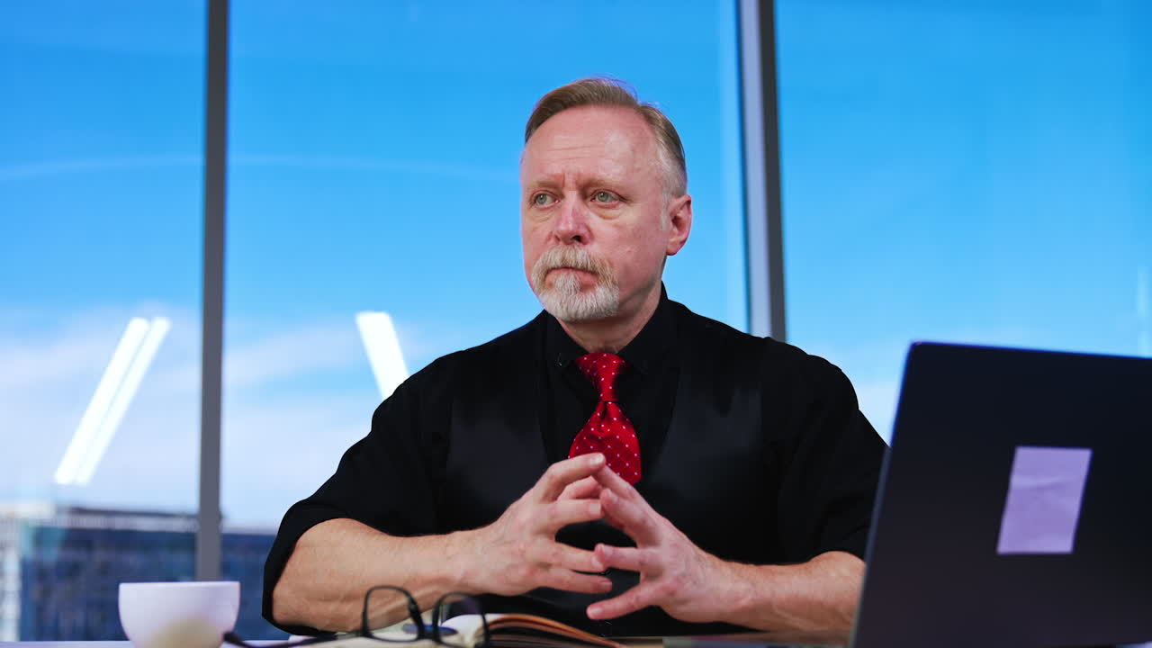 Businessman working at laptop in his office drink coffee. Strict male face expression becomes softer. Close up.