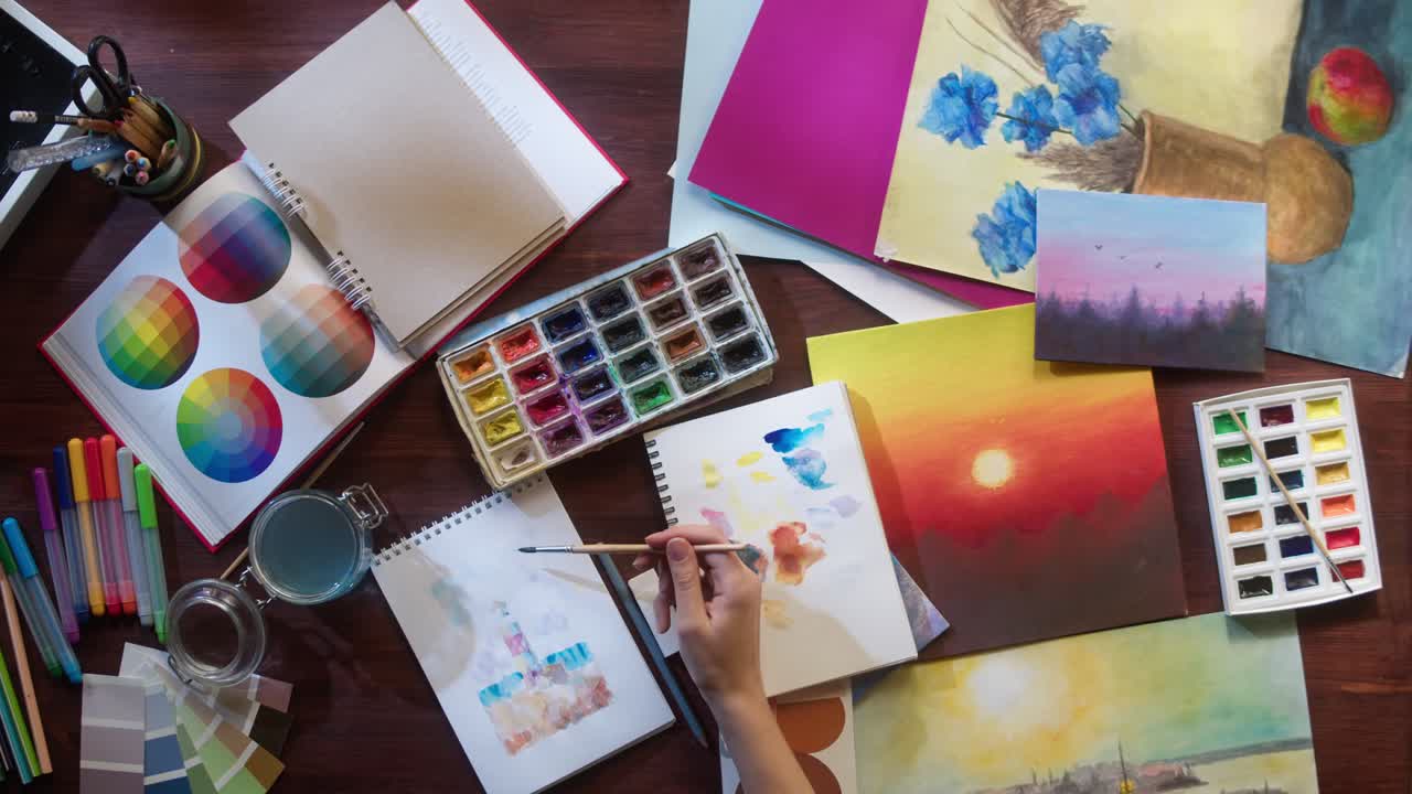 Top View of Artist Painting with Watercolors on a Creative Desk