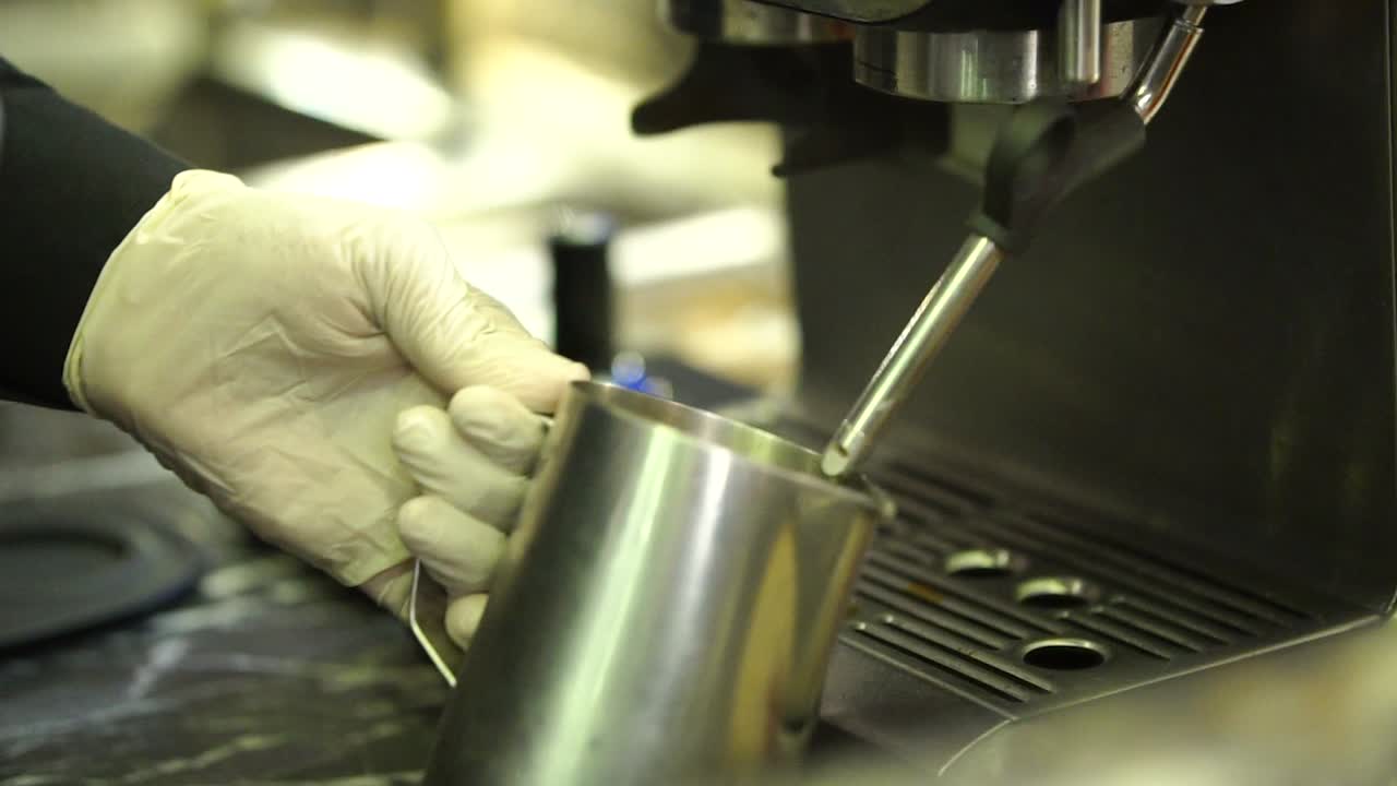 Close-Up View Of Barista Filling Up Metal Cup With Hot Milk