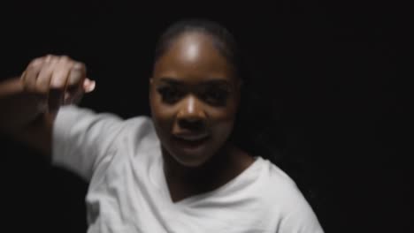 head and shoulders studio portrait shot of young woman dancing with low key lighting against black background