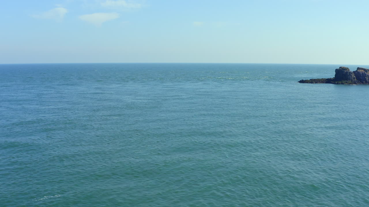 Aerial trucking shot revealing County Antrim's rocky Portmurk headland in clear sunny afternoon