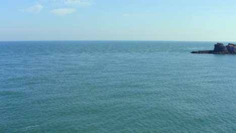 Aerial trucking shot revealing County Antrim's rocky Portmurk headland in clear sunny afternoon