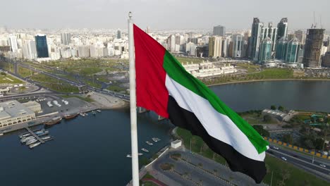 vista superior de primer plano de la bandera de los emiratos árabes unidos ondeando en el aire sobre la isla de la bandera de sharjah, el símbolo nacional de los emiratos árabes unidos, día nacional de los emiratos árabes unidos, video de 4k