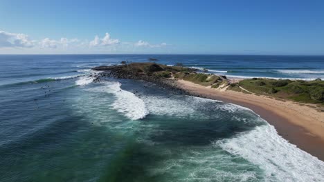 pintoresca playa de angourie point con olas espumosas salpicando en la orilla en nsw, australia - foto aérea