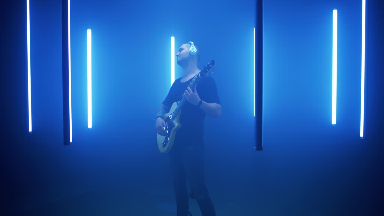 человек играет на электрической гитаре в студии синего света