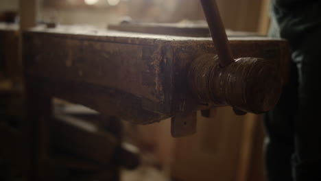 hombre presionando tabla de madera en el interior. hombre trabajando en la máquina de torno de madera en el estudio