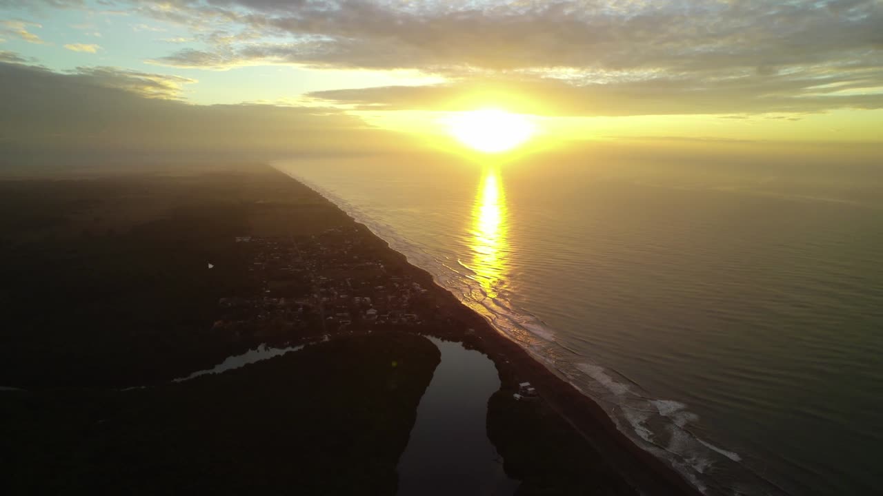 Drone-kuva, joka panoroituu vasemmalle Los Cristianoksen, Teneriffan, rannikkoa pitkin, näyttäen rantaviivan, merenpinnan ja auringonlaskun valon Atlantin valtameren yllä.