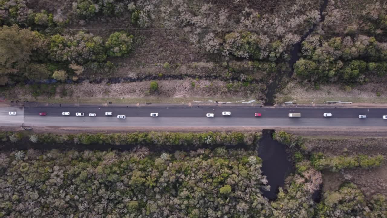 toma aérea de arriba hacia abajo del atasco de tráfico en la carretera rural en uruguay al atardecer - línea de vehículos esperando para conducir
