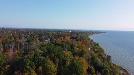 Flying-over-treed-shoreline-of-Southern-Ontario-and-freshwater-Lake-Ontario