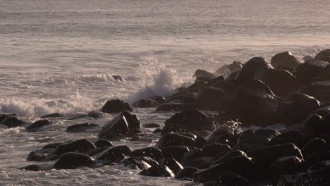 el movimiento lento de las olas chocando contra las rocas bajo un amanecer dorado.