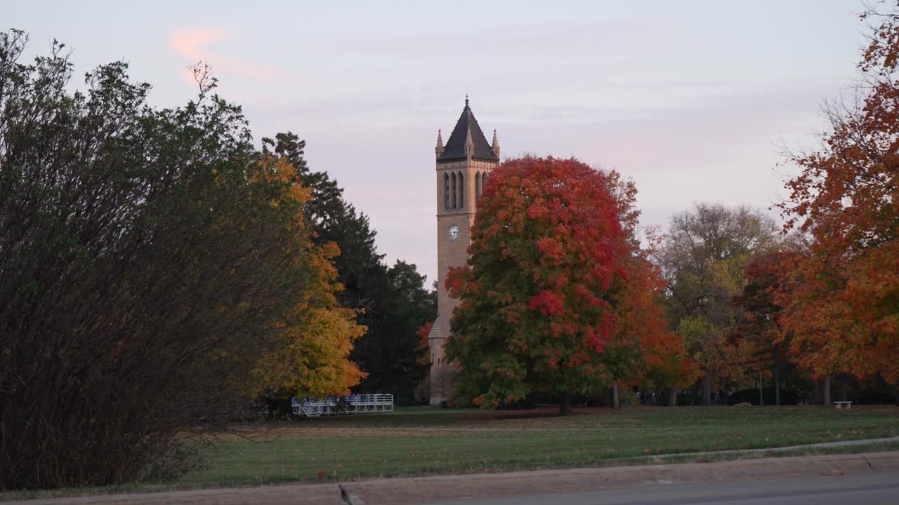 A still shot of the Campanile at Iowa State University, surrounded by vibrant autumn foliage, captured at sunset.