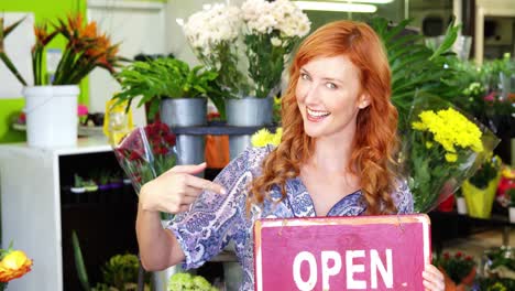 florista sonriente sosteniendo un letrero abierto en pizarra en una tienda de flores