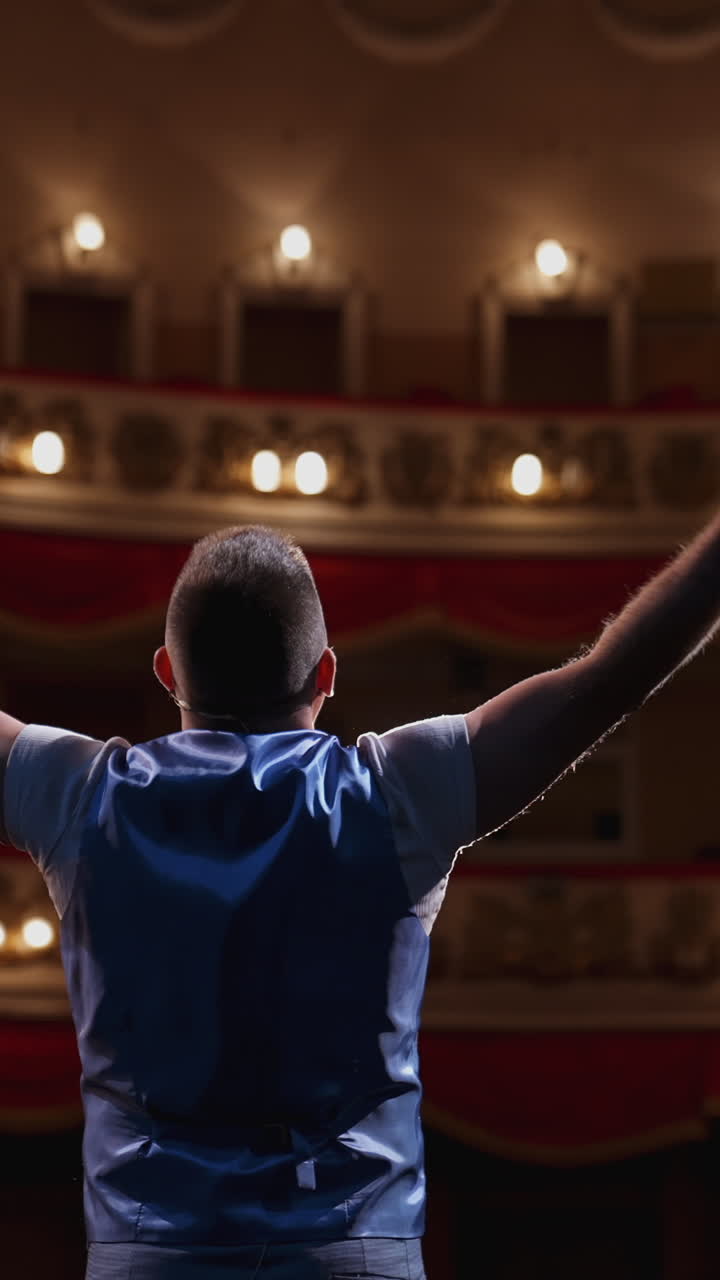Man performing with gestures on stage. Unrecognizable actor standing on stage in classic theater. Male actor speaks from the scene. Back view. Vertical video