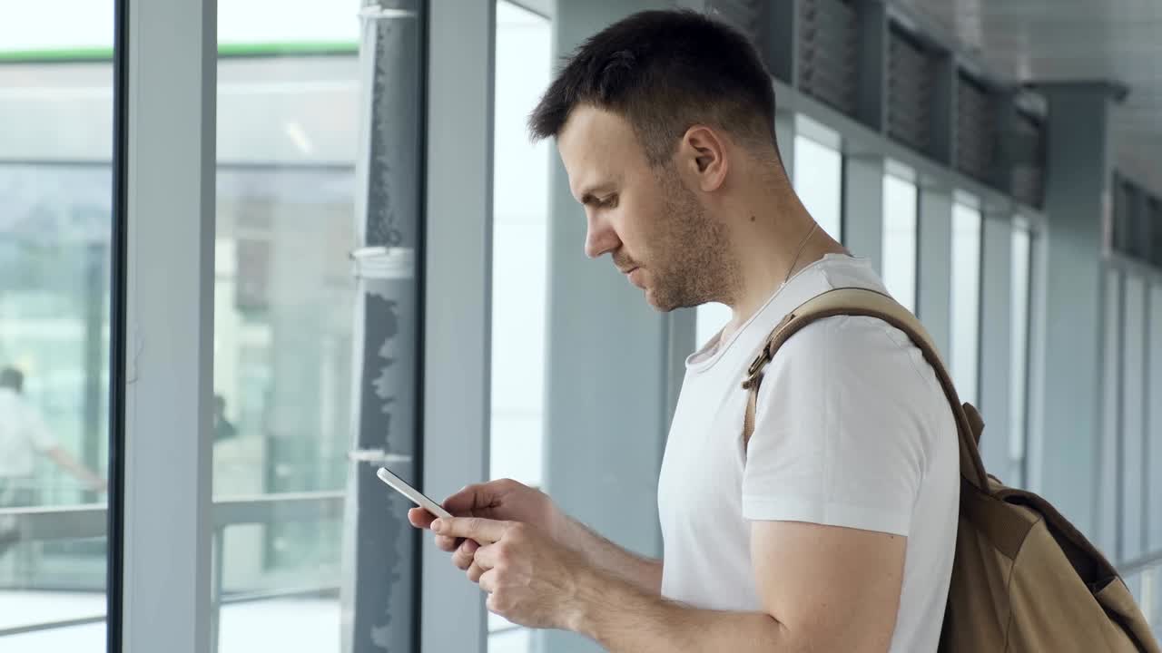 공항에서 휴대전화로 비행기 번호를 확인하는 남자, 이메일을 읽는 젊은 남자