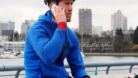 Biker-sitting-next-to-the-bike-and-talking-on-the-phone,-4K-4k