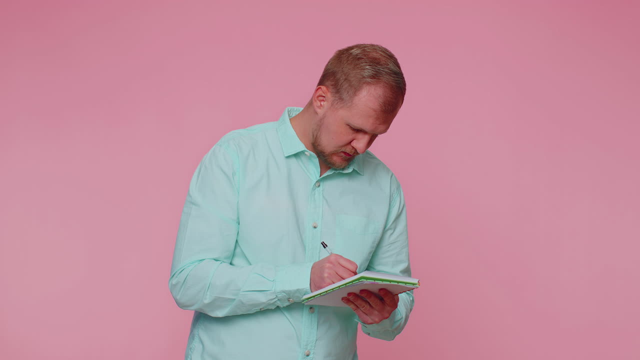 Thoughtful journalist man making notes, writing down thoughts with pen into notepad notebook diary