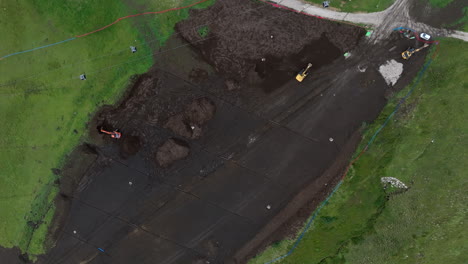 construction site excavation machinery working on ski station slope during off season, aerial birdseye view