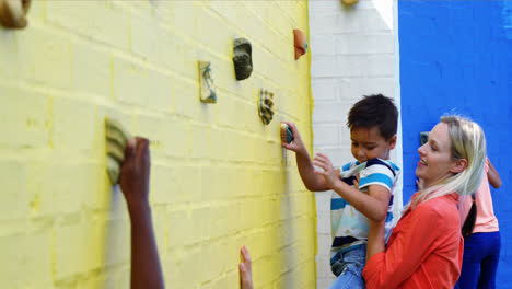 Entrenador-Ayudando-A-Los-Niños-En-La-Pared-De-Escalada