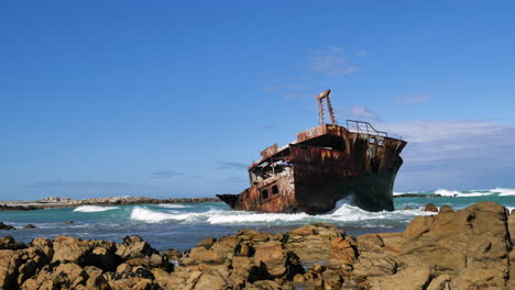 lapso de tiempo - medio naufragio viejo oxidado que se encuentra junto a la costa rocosa de l&#39;agulhas, olas corriendo, sudáfrica