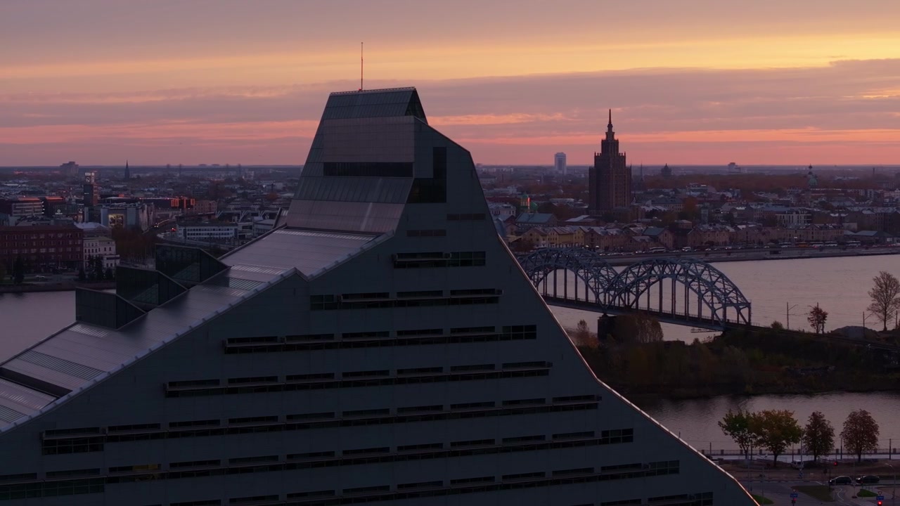 Biblioteca Nazionale della Lettonia bagnata dall'alba, con ponti che attraversano la Daugava.