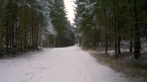 4k uhd aerial drone clip of a snowy road surrounded by trees in a forest in winter with snow covering the tree tops in bavaria, germany