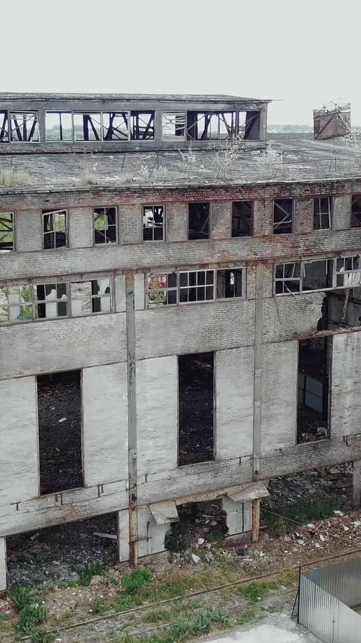 Aerial view of an old factory ruin and broken windows. Old industrial building for demolition. Vertical video