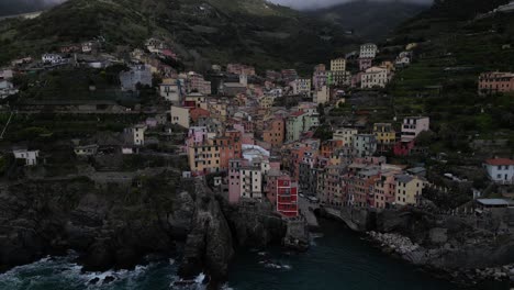 Riomaggiore-Cinque-Terre-Italy-aerial-cloudy-day-side-flight-of-village