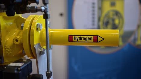 the word hydrogen on a yellow pipe which is part of a demonstrator of special shut-off valves on a trade fair, zoom in