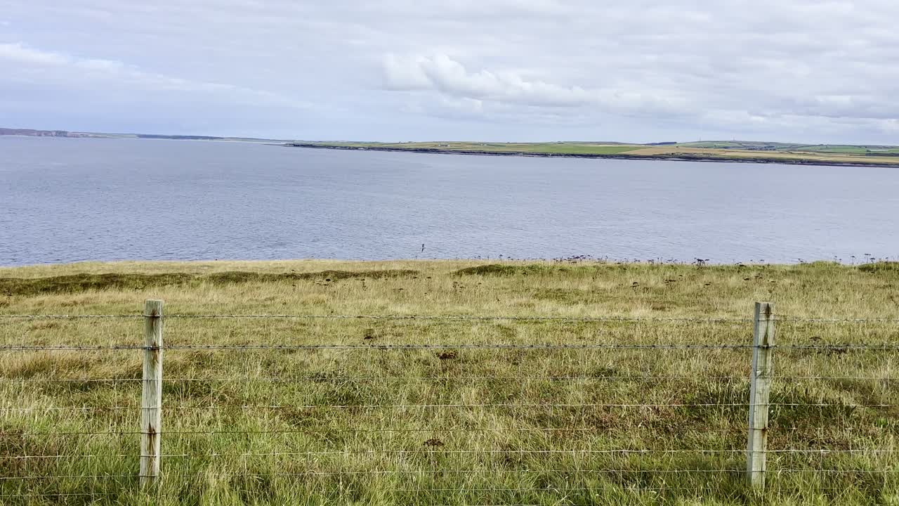 Holborn Head as viewed from a cliff walk in Scotland. Green grassy fields and beautiful skies
