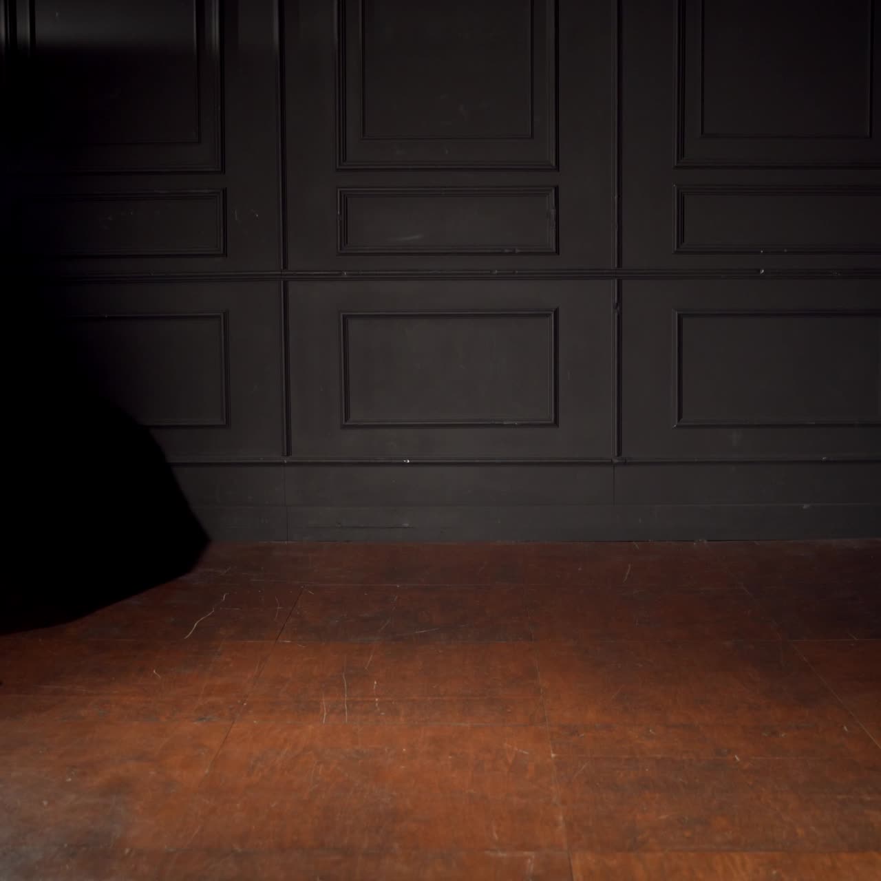 Somebody pushes new prams to the centre of the room. Modern pushchairs in dark room lit with a lamp