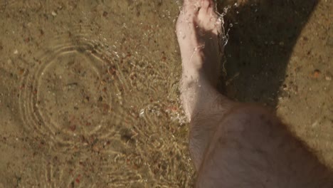 pov shot of man walking barefooted on a shallow water sunny day