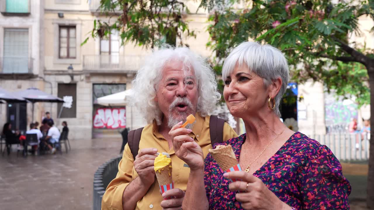 Coppia anziana felice che gusta un gelato e conversa in piazza