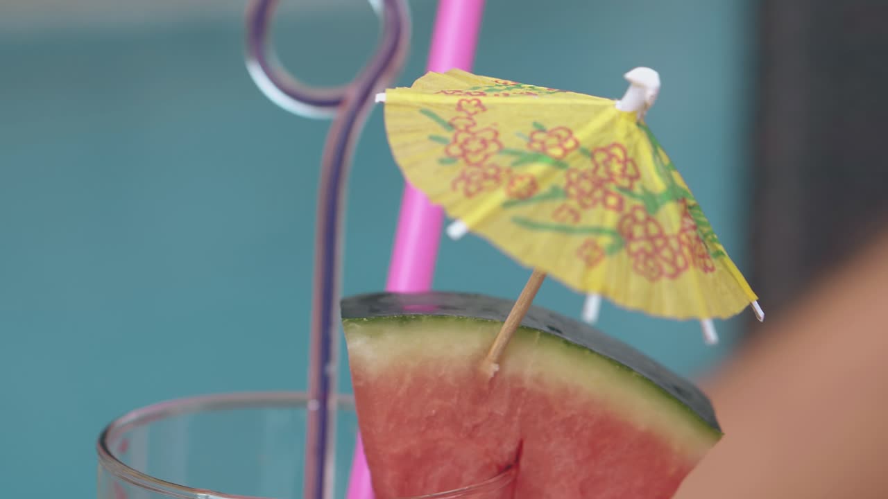 보라색 빨대와 함께 유리 음료 우산은 파란색에 대항하여 서 있습니다