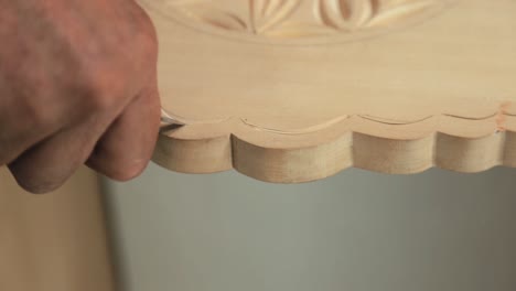 a man engraving his wooden cradle with more precise hand technique on closer view