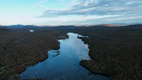 A-Lake-Embraced-by-the-Vibrant-Autumnal-Shades-of-the-Surrounding-Foliage---Aerial-Pullback