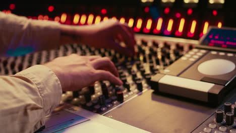 audio technician twisting pre amp knobs and buttons on board in control room